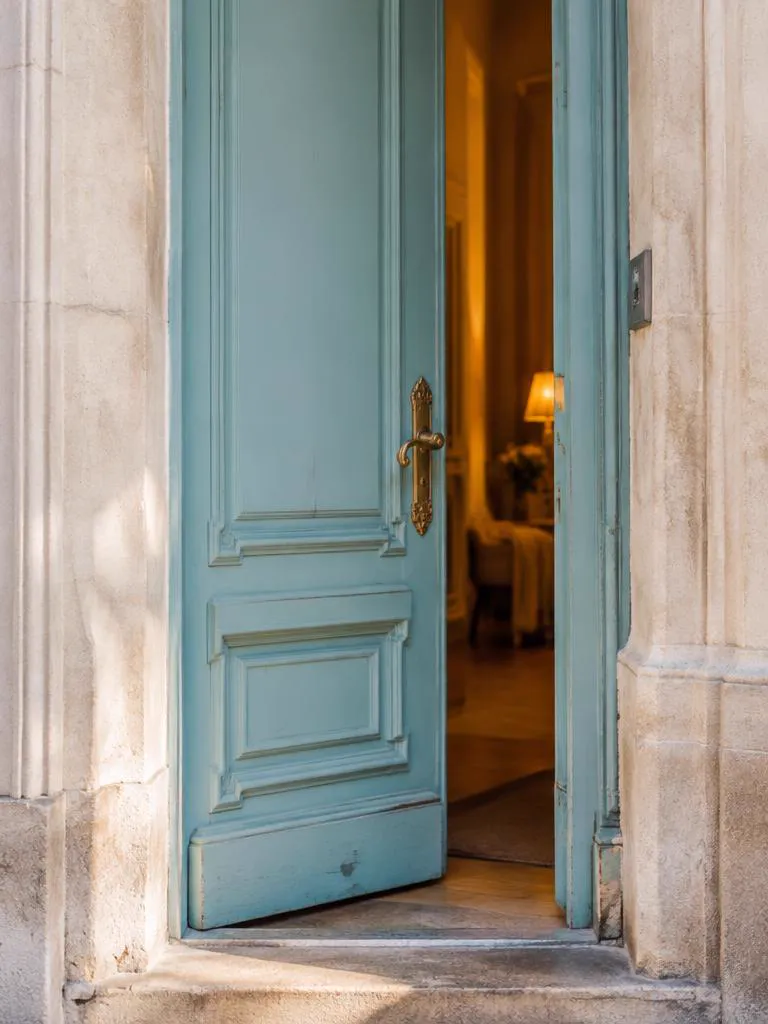 Open robin's-egg-blue Parisian door with warm light inside